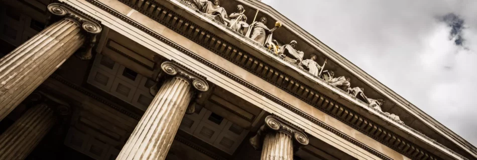 Vista desde abajo de edificio con arquitectura griega de grandes columnas.